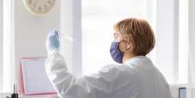 A person in a lab coat holding a test tube